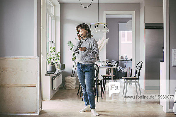 Woman standing at home talking on the phone