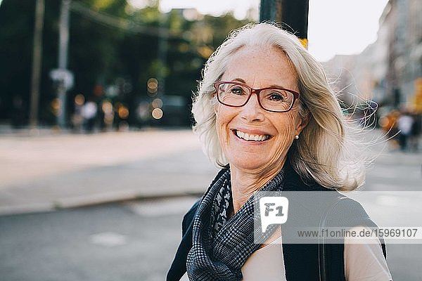 Portrait of happy wrinkled woman wearing scarf in city