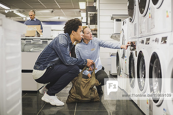 Älterer Besitzer erklärt Kunden im Elektronikgeschäft die Waschmaschine