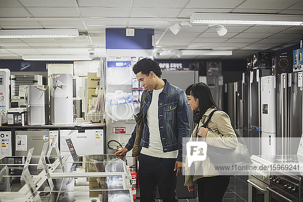 Male and female friends looking at appliances in electronics store