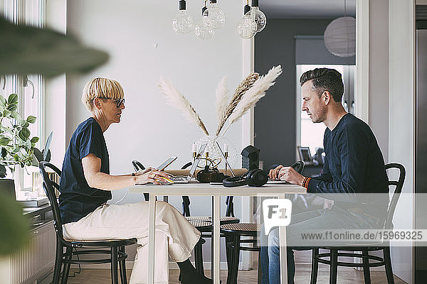 Profil von Frau und Mann bei Tisch  die von zu Hause aus arbeiten