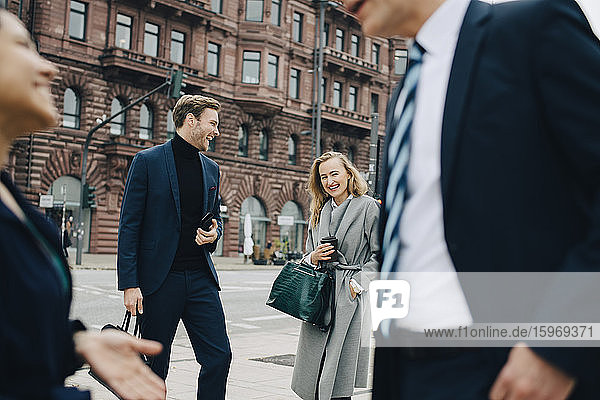 Smiling entrepreneur by male colleague standing on street in city