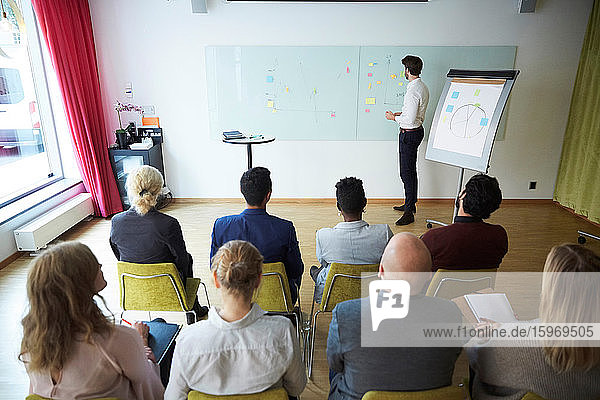High angle view of businessman giving presentation to male and female coworkers in office workshop