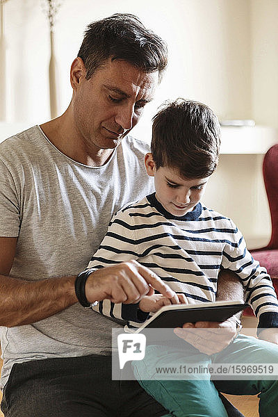 Father using tablet with son at home