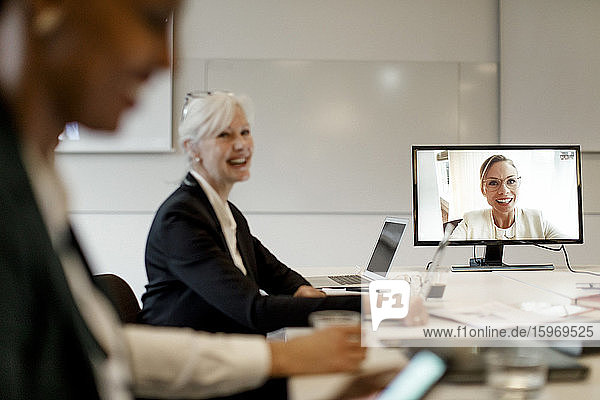 Lächelnder weiblicher Manager diskutiert mit Kollegen per Webkonferenz während eines globalen Geschäftstreffens