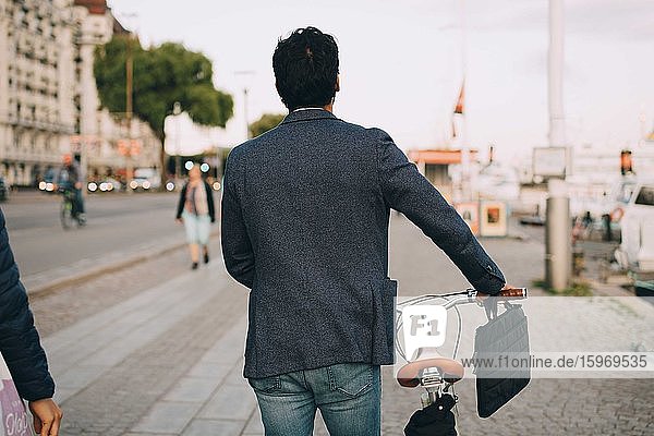 Rückansicht eines Mannes mit Fahrrad in der Stadt