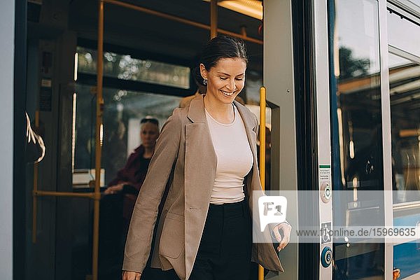 Lächelnde Frau beim Aussteigen aus der Straßenbahn während einer Stadterkundung