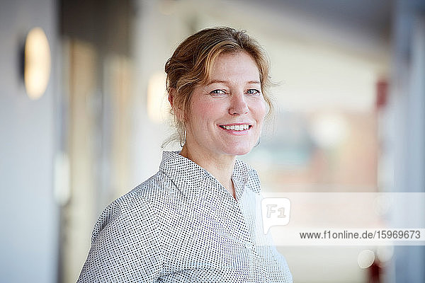 Portrait of smiling mature entrepreneur standing at workplace