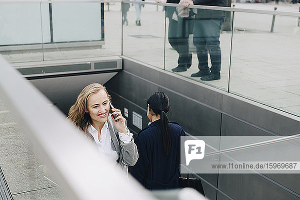 Smiling businesswoman talking through smart phone in city