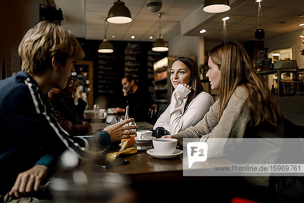 Teenager-Freunde unterhalten sich  während sie im Tischcafé sitzen