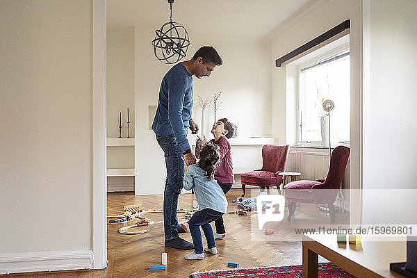 Playful children talking to father while standing at home