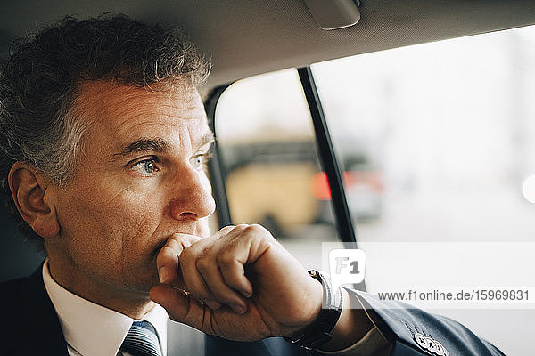 Nachdenklicher Unternehmer  der im Taxi sitzend durchs Fenster schaut