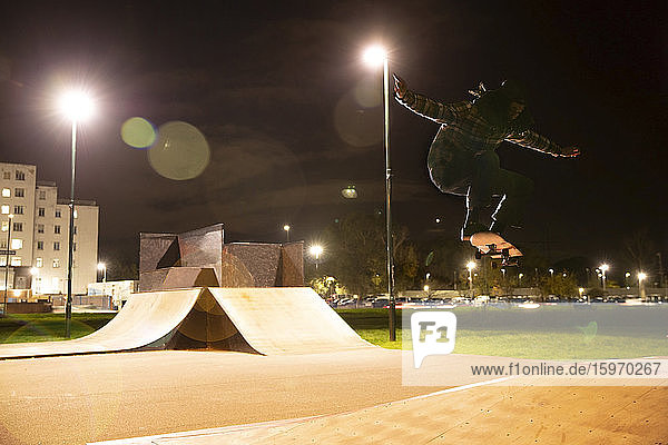 Junger Mann fährt nachts Skateboard im Skatepark