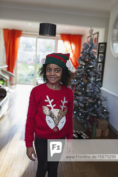 Porträt eines festlichen Mädchens in Weihnachtspullover und Hut
