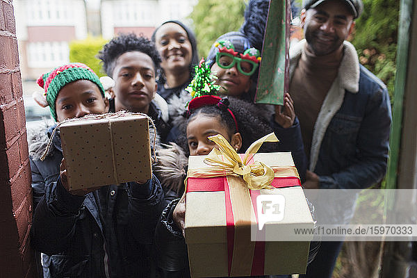 Portrait happy family delivering Christmas gifts at front stoop