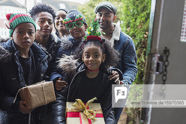 Portrait glückliche Familie beim Überreichen von Weihnachtsgeschenken vor der Haustür