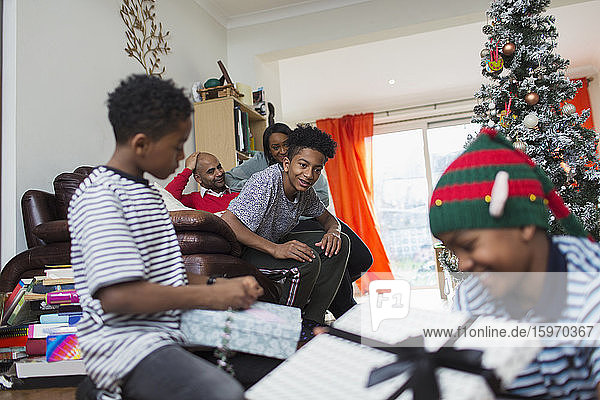 Familie öffnet Weihnachtsgeschenke im Wohnzimmer