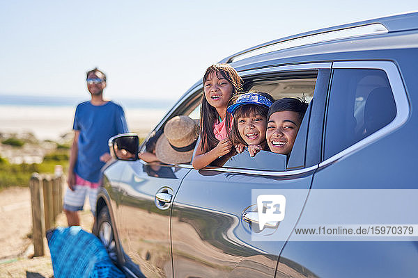 Porträt einer glücklichen Familie im Auto am sonnigen Strand