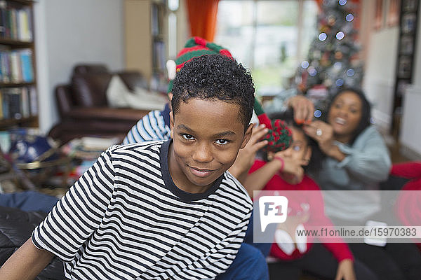 Porträt eines verspielten Jungen  der Weihnachten mit der Familie im Wohnzimmer feiert