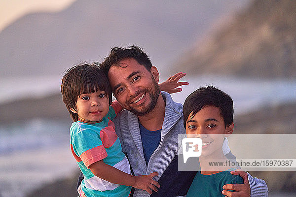 Portrait happy father and sons on beach