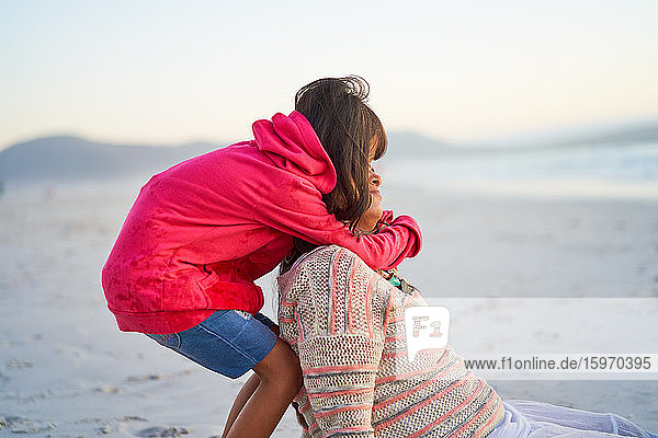 Zärtliche Tochter umarmt Mutter am Strand