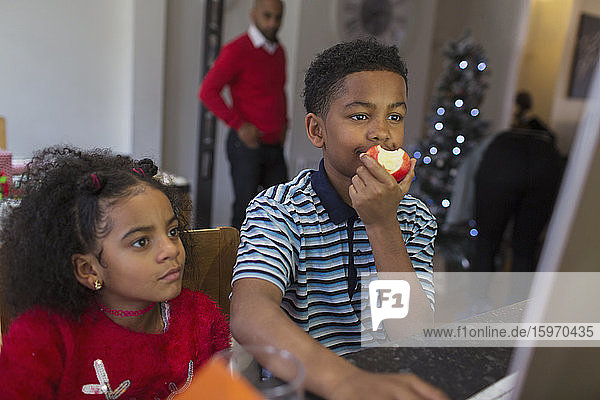 Bruder und Schwester essen Apfel am Computer