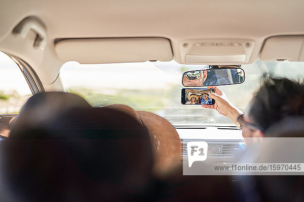 Familie nimmt Selfie mit Fotohandy im Auto mit