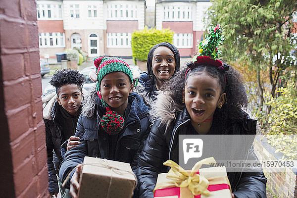 Porträt einer glücklichen Familie beim Überreichen von Weihnachtsgeschenken auf der Vordertreppe