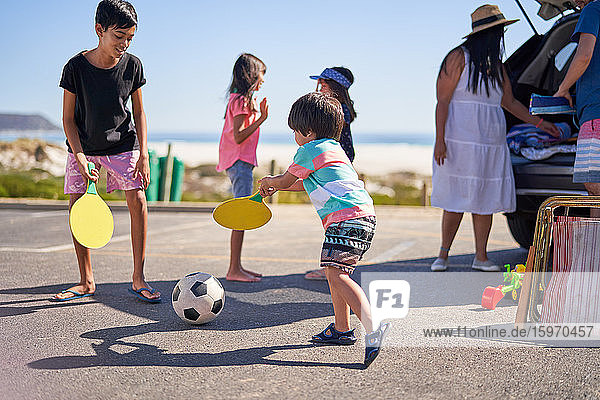 Family playing with soccer ball in beach parking lot