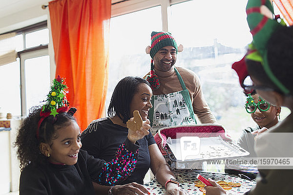 Fröhliche Familie backt und isst Weihnachtsplätzchen bei Tisch