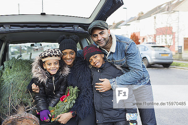 Portrait happy family loading Christmas tree in back of car
