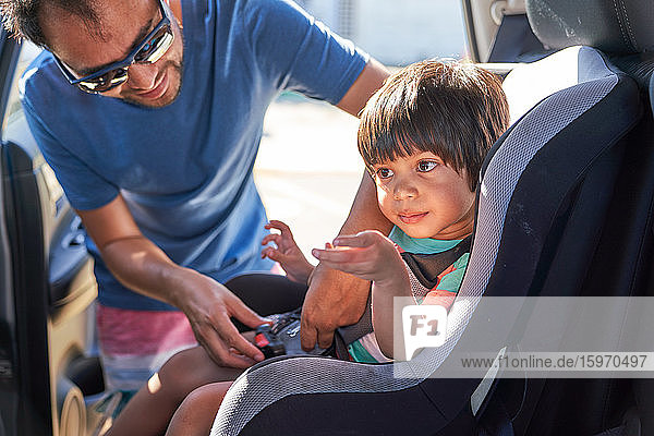 Vater befestigt Sohn im Autositz