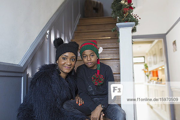 Porträt Mutter und Sohn mit Weihnachtshüten auf der Treppe zu Hause