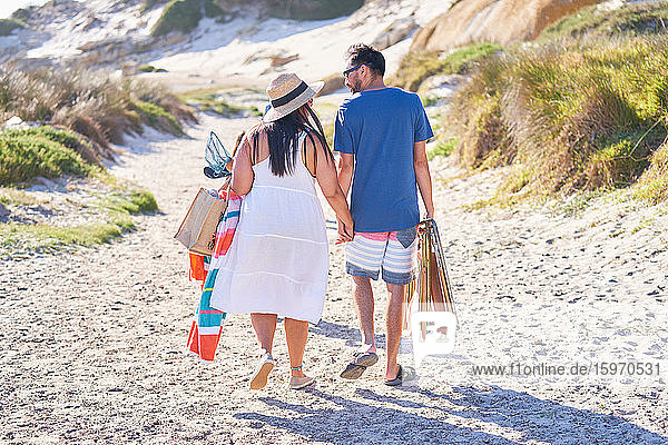 Affectionate couple walking on sunny beach path