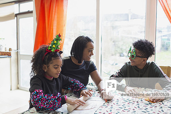 Glückliche Mutter und Söhne backen Weihnachtsplätzchen bei Tisch