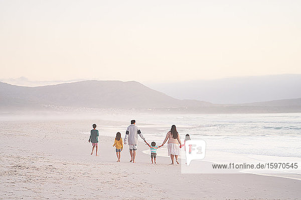 Familie hält beim Spaziergang am Strand des Ozeans Händchen  Kapstadt  Südafrika