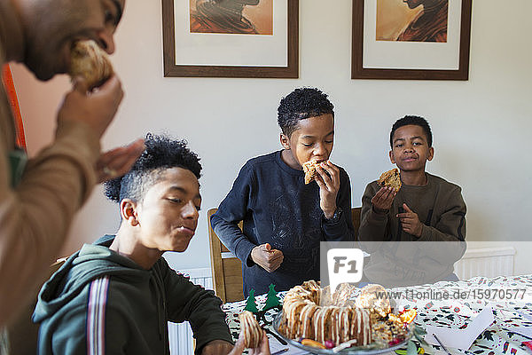 Father and sons eating Christmas cake at table