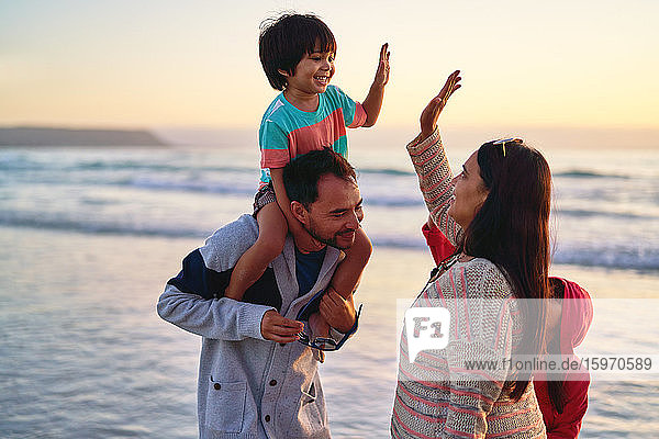 Happy family high-fiving on ocean beach