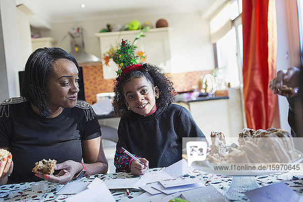 Portrait mother and daughter writing Christmas cards at table