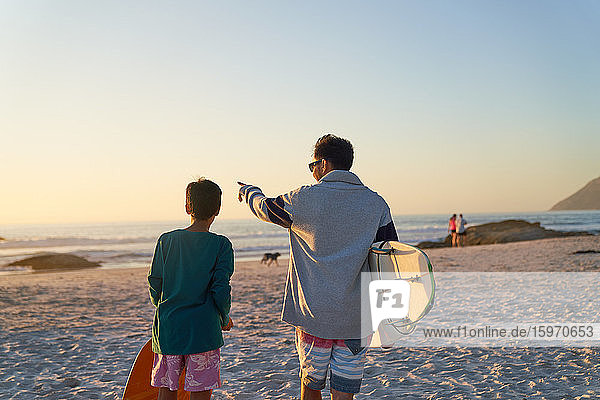 Father and son with surfboards on sunny beach