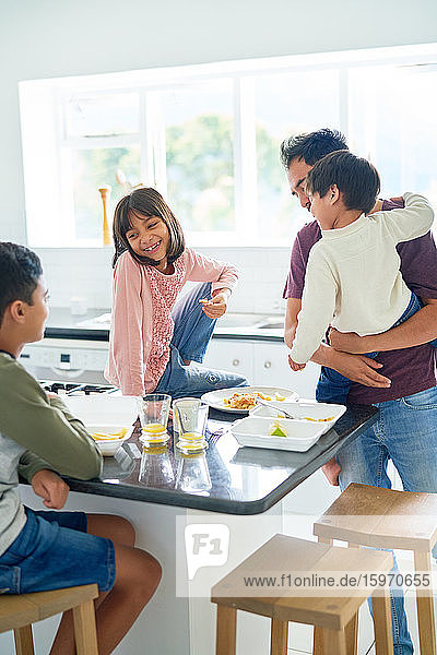 Vater und Kinder essen Essen zum Mitnehmen in der Küche