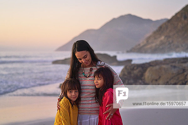 Liebevolle Mutter und Töchter umarmen sich am Strand