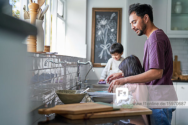 Vater und Kinder beim Abwasch an der Küchenspüle