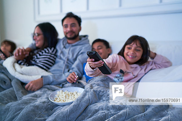 Familie entspannt sich auf dem Sofa und sieht mit Popcorn fern