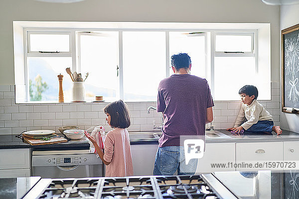 Family doing dishes at kitchen sink