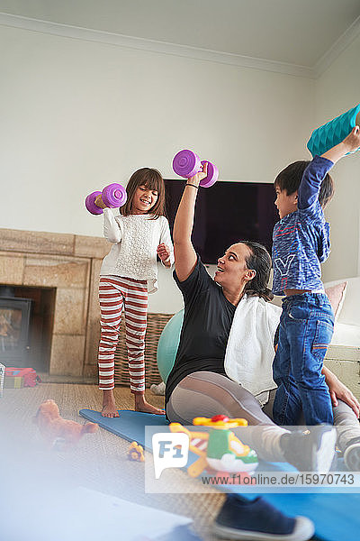 Mother and kids exercising with dumbbells in living room