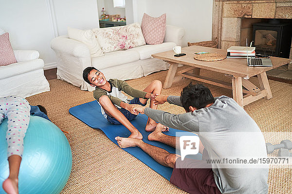 Verspielter Vater und Sohn üben auf der Yogamatte im Wohnzimmer