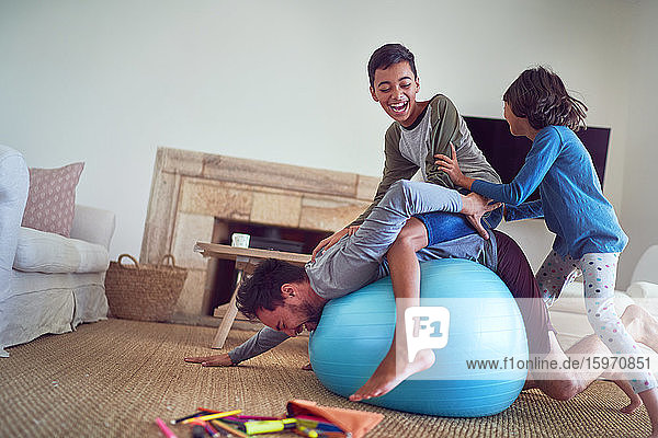 Glückliche Familie spielt im Wohnzimmer auf dem Fitnessball