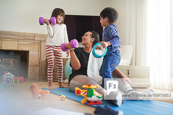 Mutter und Kinder beim Sport im Wohnzimmer
