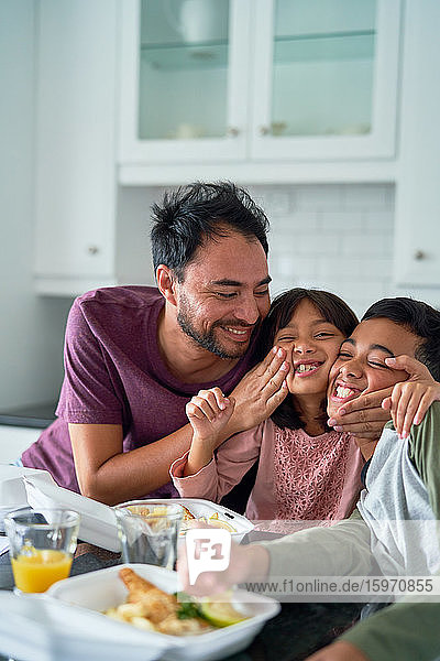 Playful happy family eating take out food in kitchen